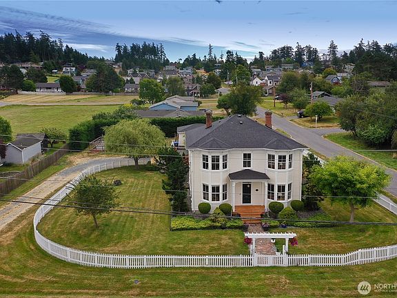 Aerial view of the residence showing the three oversized lots, manicured lawn, and the surrounding downtown Coupeville neighborhood
